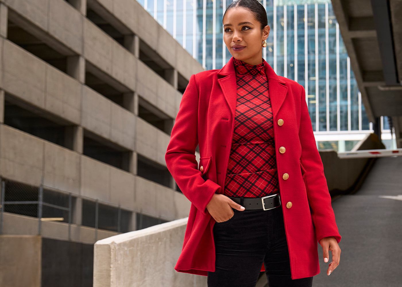 Confident woman wearing a red tailored coat with gold buttons and a plaid top, styled for effortless layering in Boston Proper fashion.