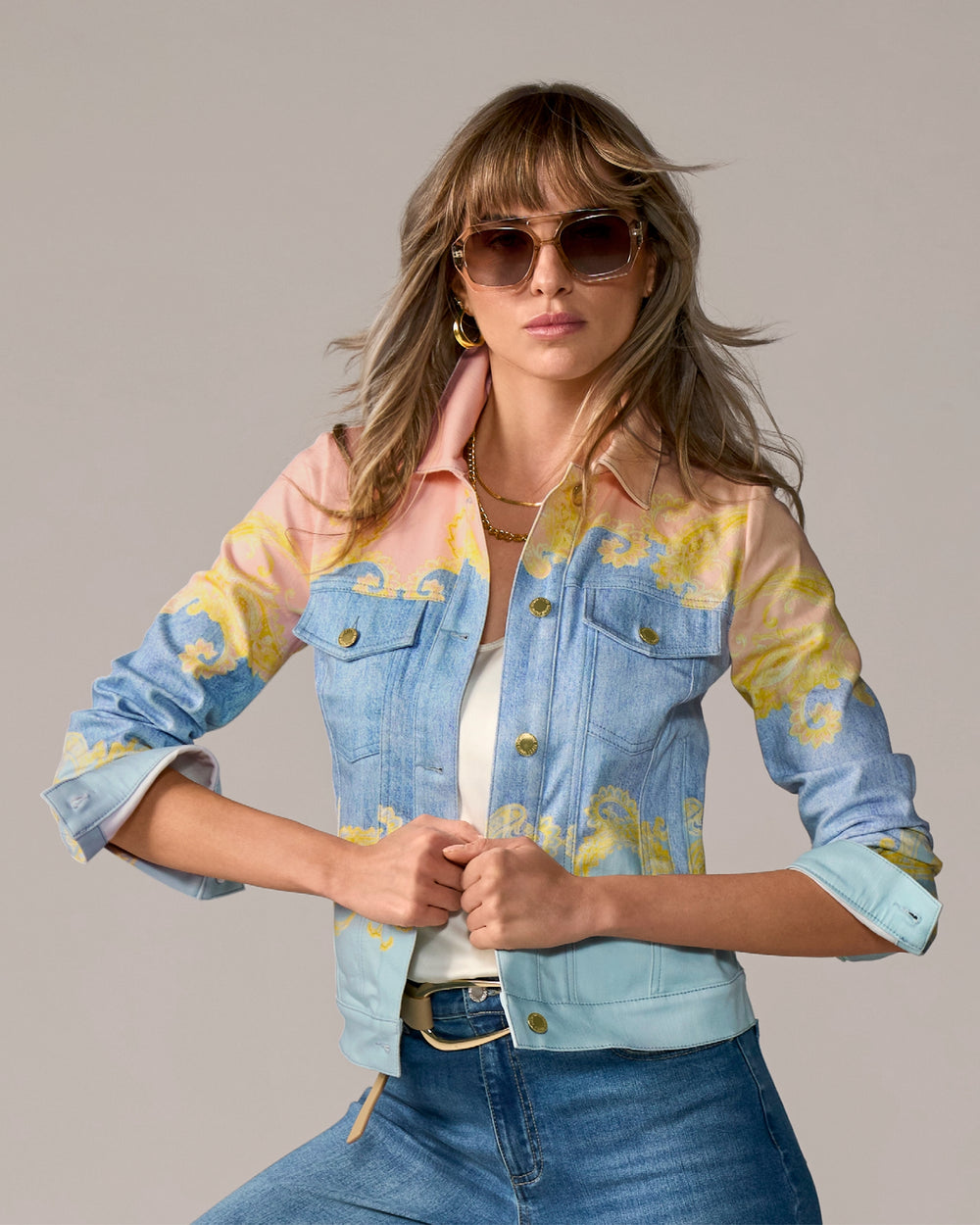 Woman wearing a colorful denim jacket with floral patterns on a gray background