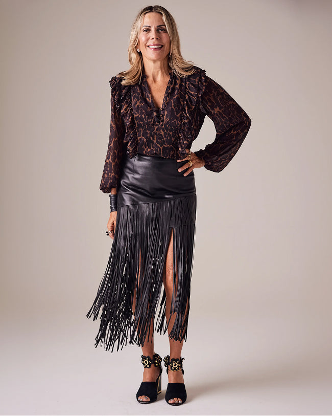 sheryl wears animal print blouse and black fringe skirt