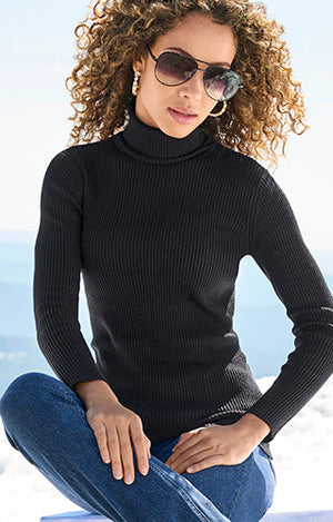 Model wearing black turtleneck top with gold hoops and medium wash jeans.