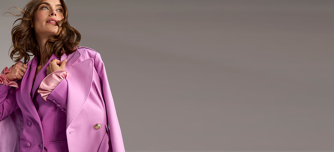 Woman wearing a pink coat against a gray background