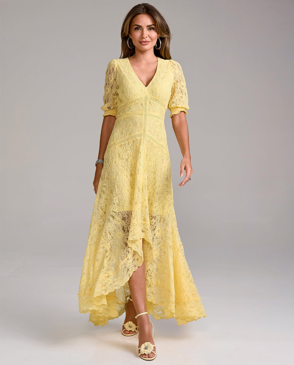 Woman wearing a yellow lace dress on a gray background