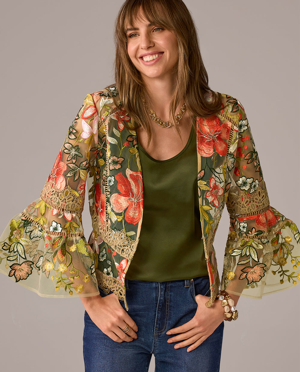 Woman wearing a floral embroidered jacket with a plain background