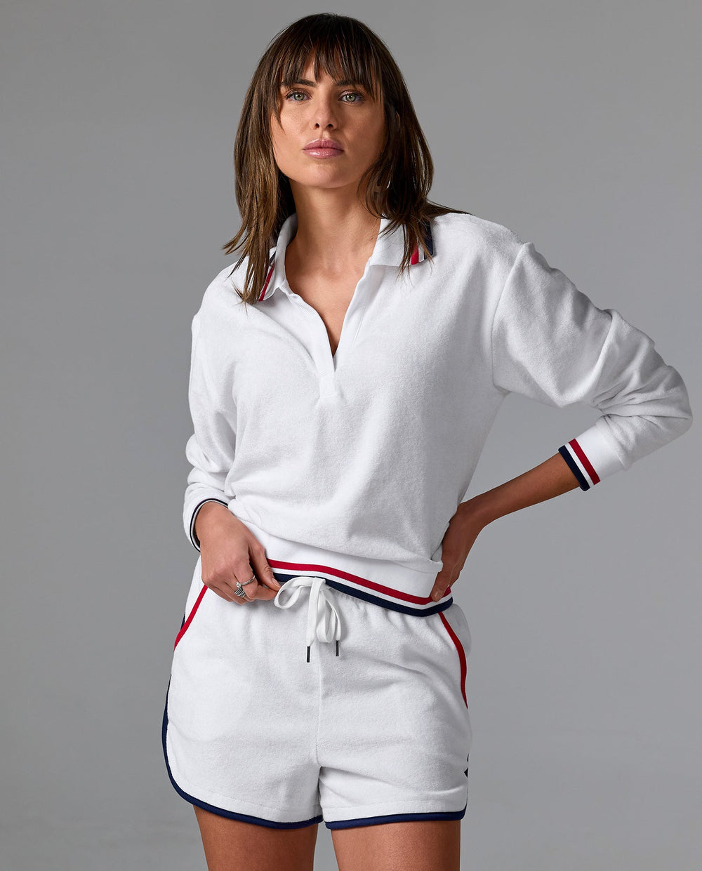 Model is wearing white, red, and blue collared long sleeve with matching drawstring shorts.