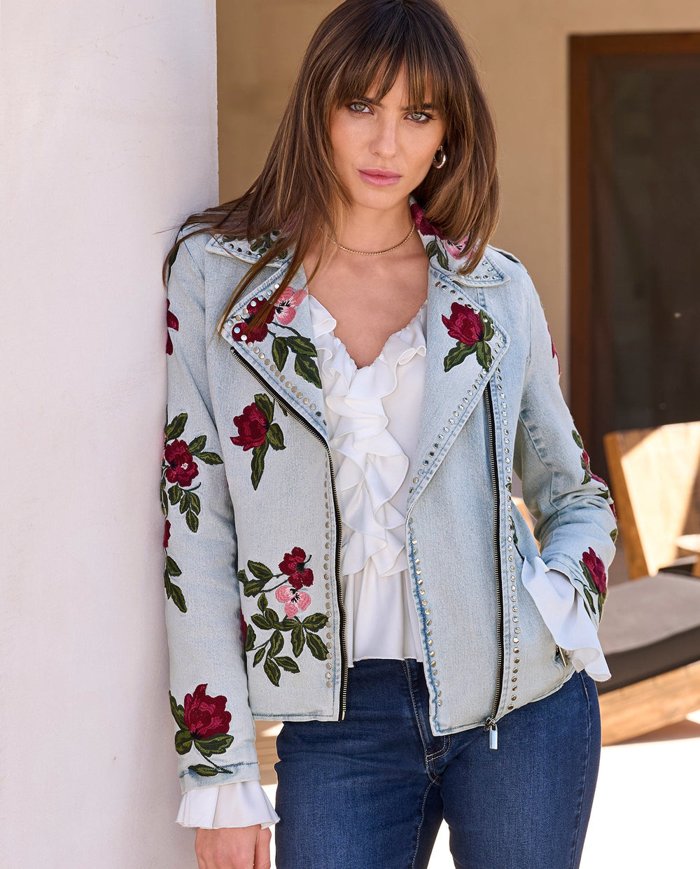 Model is wearing floral embroidered denim jacket.