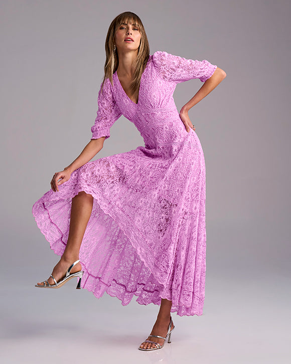 Woman wearing a pink lace dress against a gray background
