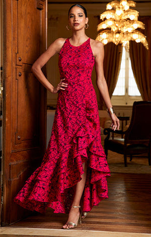 Model wearing red lace ruffle gown with silver ankle strap heels.