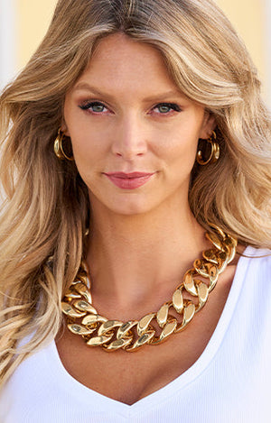 Models wearing gold hoops and a bulky chain necklace.
