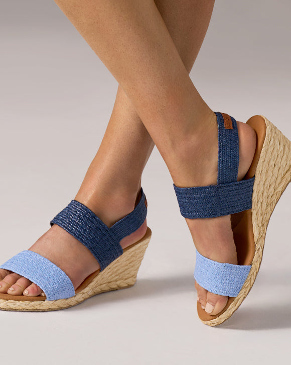 Blue wedge sandals with woven sole on a neutral background