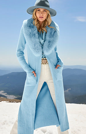 Model wearing blue hat, blue Marilyn top, blue knee length faux fur sweater, brown jeweled belt and white Monterey jeans.
